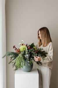 Kaboompics - Woman Arranging Christmas Greenery in a Vase