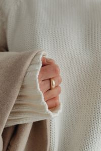 Kaboompics - Hand Holding Beige Coat Against White Sweater