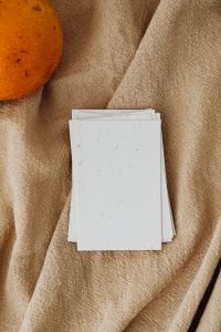 Kaboompics - Blank Business Card Stack on Beige Linen with an Orange Fruit Accent