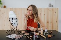 Kaboompics - Woman Applying Lipstick at a Vanity Mirror with Cosmetics Across the Table