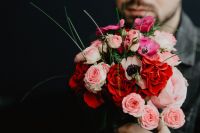 Kaboompics - Red and Pink Flower Bouquet Held by Person on Dark Background