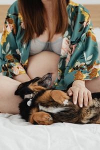 Kaboompics - Pregnant Woman Petting a Small Dog on a Bed
