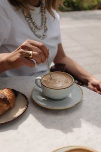 Kaboompics - Woman Stirring Cappuccino at an Outdoor Cafe