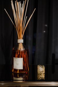 Kaboompics - Minimal Amber Reed Diffuser With Reeds On Glossy Black Surface