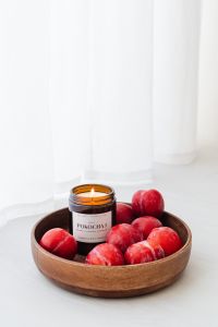 Kaboompics - Small Soy Candle and Plums on a White Table with Negative Space for Product Mockups