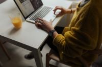 Kaboompics - Woman Typing on Laptop at White Desk with Orange Juice and Smartphone