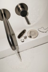 Kaboompics - Black Pump Bottle Beside Running Sink Faucet