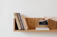 Kaboompics - Hand Holding Vintage Film Camera Above Shelf with Design Books
