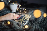Kaboompics - Warm Fairy Light Bokeh Framing a Cup and a Hygge Book