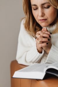 Kaboompics - Woman Praying with a Cross Necklace and Bible in Her Lap