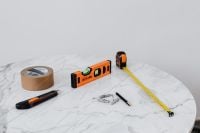 Kaboompics - DIY Home Renovation Tools on White Marble: Spirit Level, Tape Measure, Utility Knife and Wall Anchors