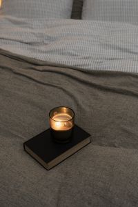 Kaboompics - Close-Up Candle on a Gray Bed with a Book