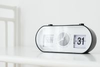 Kaboompics - White Retro Flip Calendar Clock on a Bright Table with Left-Side Copy Space