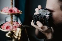 Kaboompics - Man Photographer Capturing a Pink Rose Display with a Silver Camera