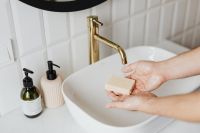 Kaboompics - Displaying a Bar of Soap in Open Hands beside Bathroom Soap Dispensers, Hygiene Product Photo