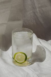 Kaboompics - Clear Lime Water Glass on White Linen with a Defined Sunlit Shadow, Minimal Lifestyle Still Life