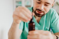 Kaboompics - Doctor Handling Dropper Bottle at Medical Desk