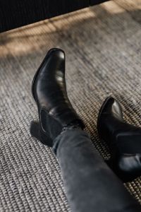 Kaboompics - Single Black Leather Ankle Boot with Block Heel on Textured Rug
