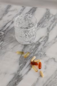 Kaboompics - Scattered Vitamins and Capsules Beside Water Glass