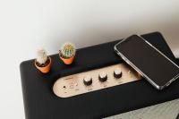 Kaboompics - Black speaker on marble table, white wall, mobile phone, cacstus