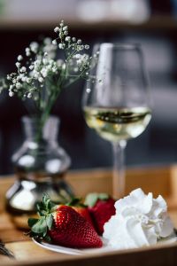 Kaboompics - Strawberries with cream and glass of white wine on wooden tray