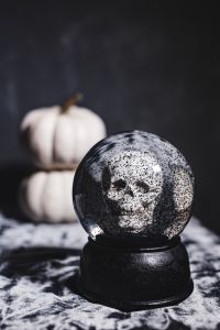 Kaboompics - Skull Snow Globe and White Pumpkin on Moody Halloween Background with Copy Space