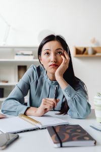 Kaboompics - Pensive Asian Woman Resting Her Head While Holding a Pen at Her Desk