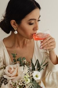 Kaboompics - Bride Sipping a Pink Drink With a Rose and Greenery Bouquet