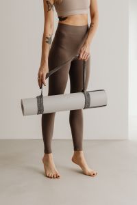 Kaboompics - Full Body Woman Holding a Rolled Yoga Mat by Its Strap