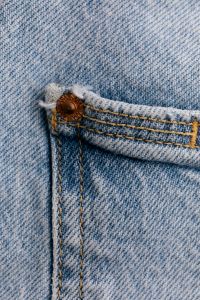 Kaboompics - Copper Rivet on Jeans Pocket Seam, Light Wash Denim Stitching Close-Up