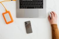Kaboompics - Man works on a computer at his desk, mobile phone, portable hard drive