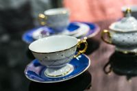 Kaboompics - White and Blue Teacup and Saucer with Gold Handle on Glossy Black Table