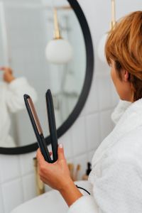 Kaboompics - Close-Up of a Woman Holding a Hair Straightener in a White Bathroom