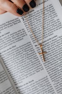 Kaboompics - Gold Chain and Black-Manicured Hand over Bible Text