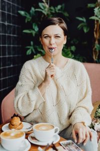 Kaboompics - Woman Pausing with a Forkful of Cafe Dessert beside Her Latte