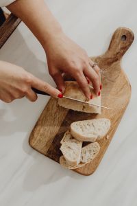 Kaboompics - Woman Slicing Bread on a Wooden Board
