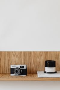Kaboompics - Vintage Olympus Film Camera and Candle on Minimalist Wooden Shelf