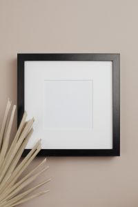 Kaboompics - Black Empty Picture Frame on Beige Wall with Dried Palm Leaves, Vertical Mockup
