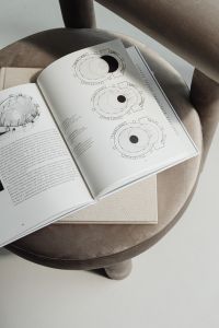 Kaboompics - Open Book with Technical Drawings on Greige Armchair