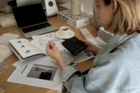 Kaboompics - Designer Holding Black Stone Sample beside Architectural Sketches and Coffee