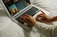 Kaboompics - Female Hands Typing on Laptop on White Bed Sheets