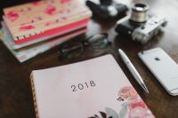 Kaboompics - Pink Floral Notebooks with Vintage Cameras, Eyeglasses, Smartphone and Pen on Wood