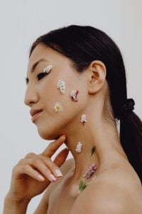 Kaboompics - Asian Woman Side Profile with Flower Petals on Cheek and Neck, Hand at Chin