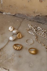 Kaboompics - Gold and Silver Rings, Pearl Drop Earrings and Chains on Stone, Minimalist Jewelry Flat Lay