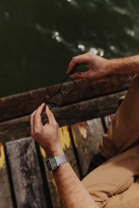 Kaboompics - Close-Up Hands Taking Off Black Eyeglasses by the Lake, Calculator Wristwatch Detail