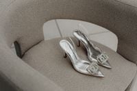 Kaboompics - Silver Slingback Heels Styled on a Gray Upholstered Chair