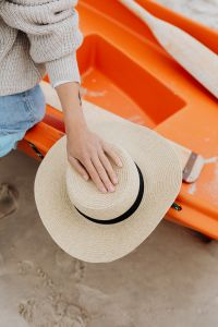 Kaboompics - Close-Up of a Hand Resting on a Straw Sun Hat in an Orange Kayak at the Beach