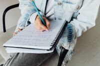 Kaboompics - Hands Writing Homework in Spiral Notebook