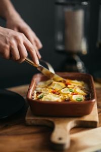 Kaboompics - Hands Serving Lemon Fish Casserole for Dinner