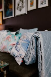 Kaboompics - Gray Quilted Throw and Blue Cushions on a Sofa beneath Framed Wall Art